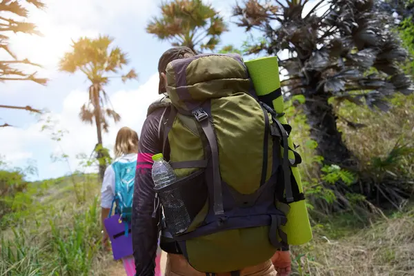 Genç bir çift okyanus manzarası sunan engebeli kayalık bir uçurumda yürüyüş yapıyor..