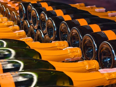 Şampanyaların çeşitleri zarif bir şekilde ahşap bir rafta dizilmiştir..