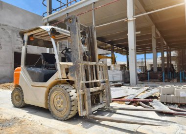 İnşaat halindeki bir binanın önüne bir forklift park edilmiş..