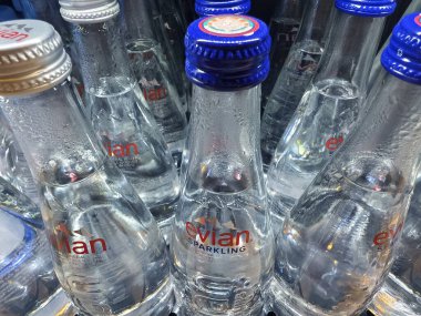 FUKET, THAILAND - 8 Mart 2025: Evian maden suyu şişeleri düzgünce bir rafa dizilmiştir.