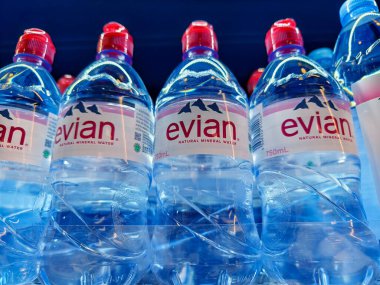 FUKET, THAILAND - 8 Mart 2025: Evian maden suyu şişeleri düzgünce bir rafa dizilmiştir.