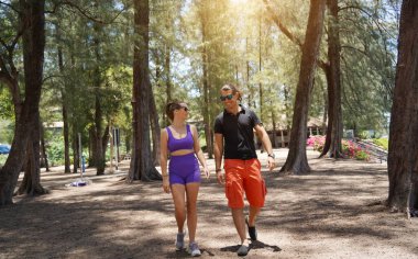 Bir adam ve bir kadın parkta birlikte esneme egzersizleri yapıyorlar..