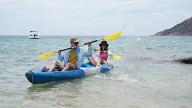 Genç çift, açık mavi bir kanoyla birlikte sarı raketlerle mutlu bir şekilde yol alıyorlar..