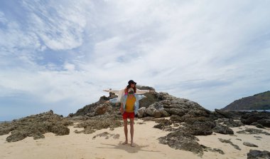 Genç bir çift kumsalda boş boş yürüyor, el ele tutuşuyor ve sıcak güneşin tadını çıkarıyor..