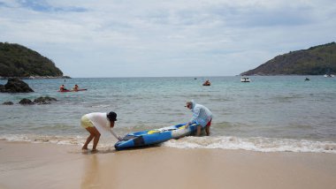 Genç bir çift deniz yolculuğu için mavi bir kano fırlatıyor..