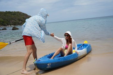 Genç bir çift deniz yolculuğundan sonra sudan bir kano çıkarıyorlar..