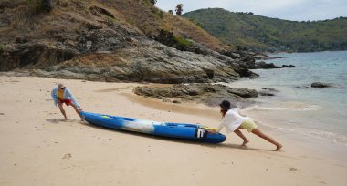 Genç bir çift deniz yolculuğundan sonra sudan bir kano çıkarıyorlar..