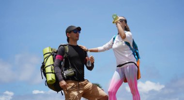 Genç bir çift okyanus manzarası sunan engebeli kayalık bir uçurumda yürüyüş yapıyor..