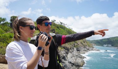 Bir erkek ve bir kadın dikkatle dürbünle uzaktan ilginç bir şeye bakıyorlar..