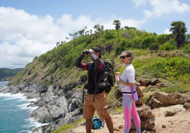 Bir erkek ve bir kadın dikkatle dürbünle uzaktan ilginç bir şeye bakıyorlar..