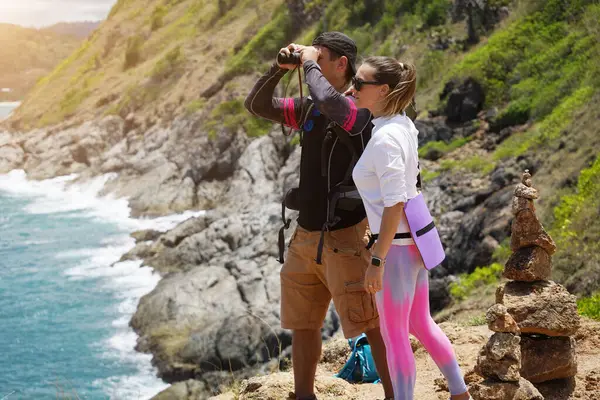 Bir erkek ve bir kadın dikkatle dürbünle uzaktan ilginç bir şeye bakıyorlar..