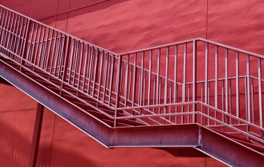 Büyük kırmızı bir duvara tırmanan bir merdiven seti..