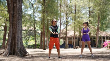 Genç çift parkta direniş bantlarıyla egzersiz yapıyor..