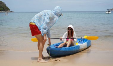 Genç bir çift deniz yolculuğundan sonra sudan bir kano çıkarıyorlar..
