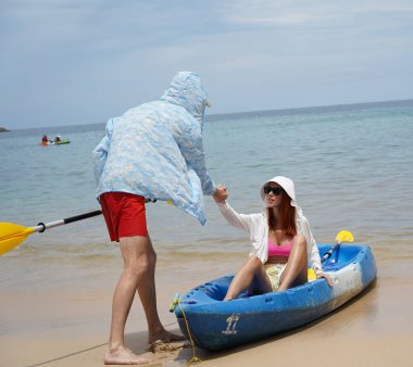 Genç bir çift deniz yolculuğundan sonra sudan bir kano çıkarıyorlar..