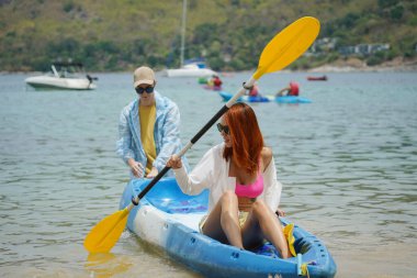 Genç bir çift deniz yolculuğu için mavi bir kano fırlatıyor..