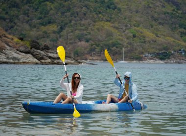 Genç çift, açık mavi bir kanoyla birlikte sarı raketlerle mutlu bir şekilde yol alıyorlar..