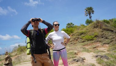 Bir erkek ve bir kadın dikkatle dürbünle uzaktan ilginç bir şeye bakıyorlar..