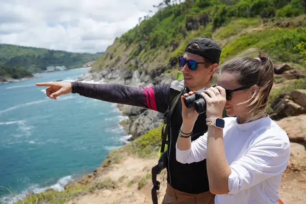 Bir erkek ve bir kadın dikkatle dürbünle uzaktan ilginç bir şeye bakıyorlar..
