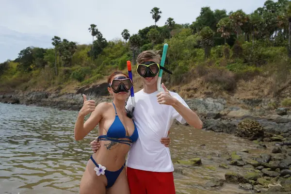 Bir adam ve bir kadın dalmadan önce gözlük ve şnorkel takıyor..