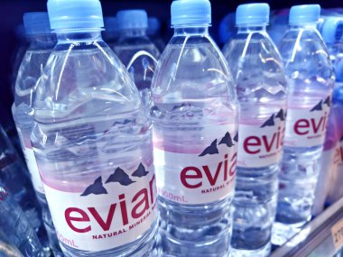 FUKET, THAILAND - 8 Mart 2025: Evian maden suyu şişeleri düzgünce bir rafa dizilmiştir.