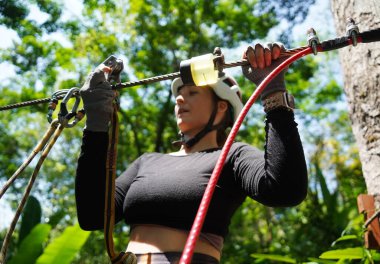 Kadın, etrafını saran kalın ormandan geçen bir halatla neşeli bir yolculuğun tadını çıkarıyor..