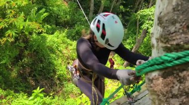 Kadın, etrafını saran kalın ormandan geçen bir halatla neşeli bir yolculuğun tadını çıkarıyor..