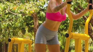 Bir adam ve kadın parkta bir makinede birlikte egzersiz yapıyorlar..