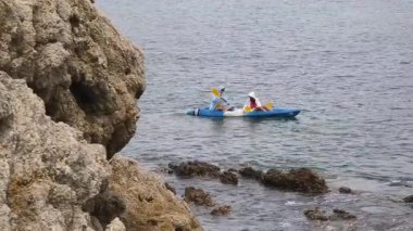 Genç çift, açık mavi bir kanoyla birlikte sarı raketlerle mutlu bir şekilde yol alıyorlar..