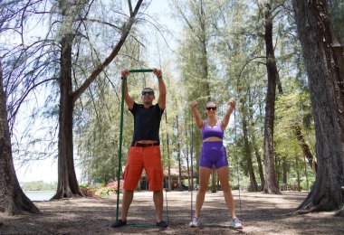 Genç çift parkta direniş bantlarıyla egzersiz yapıyor..