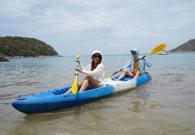 Genç çift, açık mavi bir kanoyla birlikte sarı raketlerle mutlu bir şekilde yol alıyorlar..