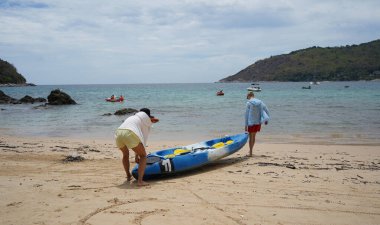 Genç bir çift deniz yolculuğu için mavi bir kano fırlatıyor..