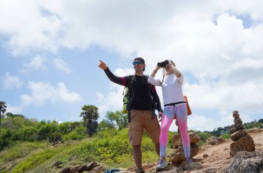 Bir erkek ve bir kadın dikkatle dürbünle uzaktan ilginç bir şeye bakıyorlar..