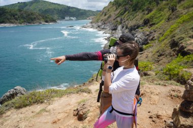 Bir erkek ve bir kadın dikkatle dürbünle uzaktan ilginç bir şeye bakıyorlar..