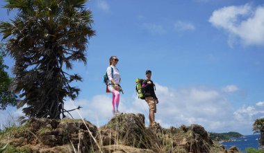Genç bir çift okyanus manzarası sunan engebeli kayalık bir uçurumda yürüyüş yapıyor..