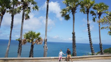 Muhteşem palmiye ağaçlarının önünde genç bir çift yan yana duruyor..