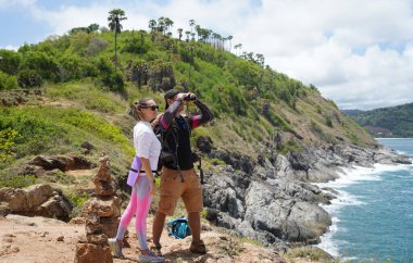 Bir erkek ve bir kadın dikkatle dürbünle uzaktan ilginç bir şeye bakıyorlar..