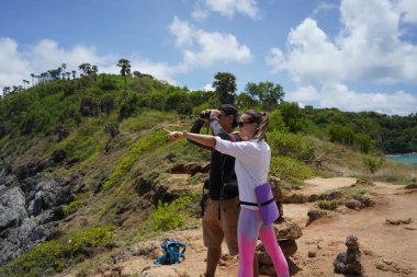 Bir erkek ve bir kadın dikkatle dürbünle uzaktan ilginç bir şeye bakıyorlar..