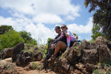 Genç bir çift okyanus manzarası sunan engebeli kayalık bir uçurumda yürüyüş yapıyor..