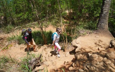 Genç bir çift okyanus manzarası sunan engebeli kayalık bir uçurumda yürüyüş yapıyor..