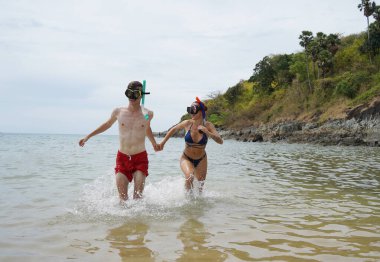 Bir adam ve bir kadın gözlük takıyor ve suyun tadını çıkarıyorlar..