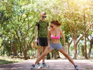 Bir adam ve bir kadın parkta birlikte koştuktan sonra bacaklarını açıyorlar..