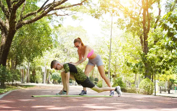 Bir adam ve bir kadın parkta birlikte koştuktan sonra bacaklarını açıyorlar..