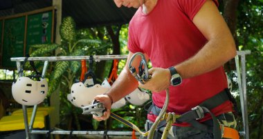 Bir adam heyecanlı bir tırmanışa dikkatle hazırlanır, güvenliğini sağlar..