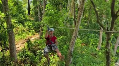 İnsanoğlu, etrafını saran kalın ormandan geçen bir ip üzerinde keyifli bir yolculuğun tadını çıkarıyor..
