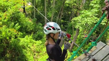 Kadın, etrafını saran kalın ormandan geçen bir halatla neşeli bir yolculuğun tadını çıkarıyor..