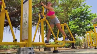 Bir adam ve kadın parkta bir makinede birlikte egzersiz yapıyorlar..