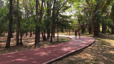 Bir adam ve bir kadın güzel bir parkta birlikte koşuyorlar, temiz havanın tadını çıkarıyorlar.