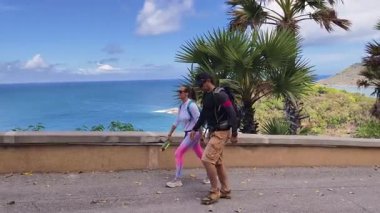 Bir erkek ve bir kadın, doğa güzelliği ve sükunetle çevrili bir yolda rahatça yürüyorlar..