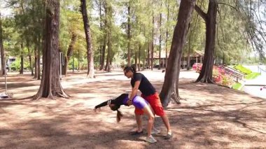 Bir adam ve bir kadın parkta birlikte esneme egzersizleri yapıyorlar..